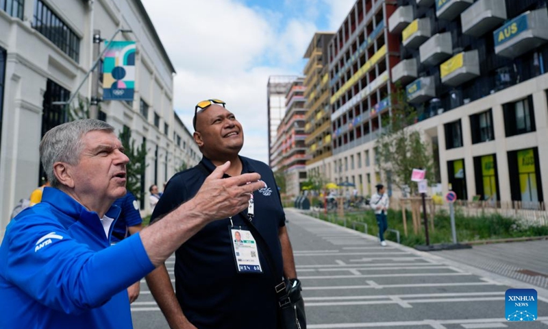 IOC President Thomas Bach (L) talks to Continental Association staff member Meli Cavu outside the team's housing in the Olympic Village ahead of the Paris 2024 Olympic Games, on July 22, 2024, in Paris, France. (Photo by David Goldman/POOL/Xinhua)