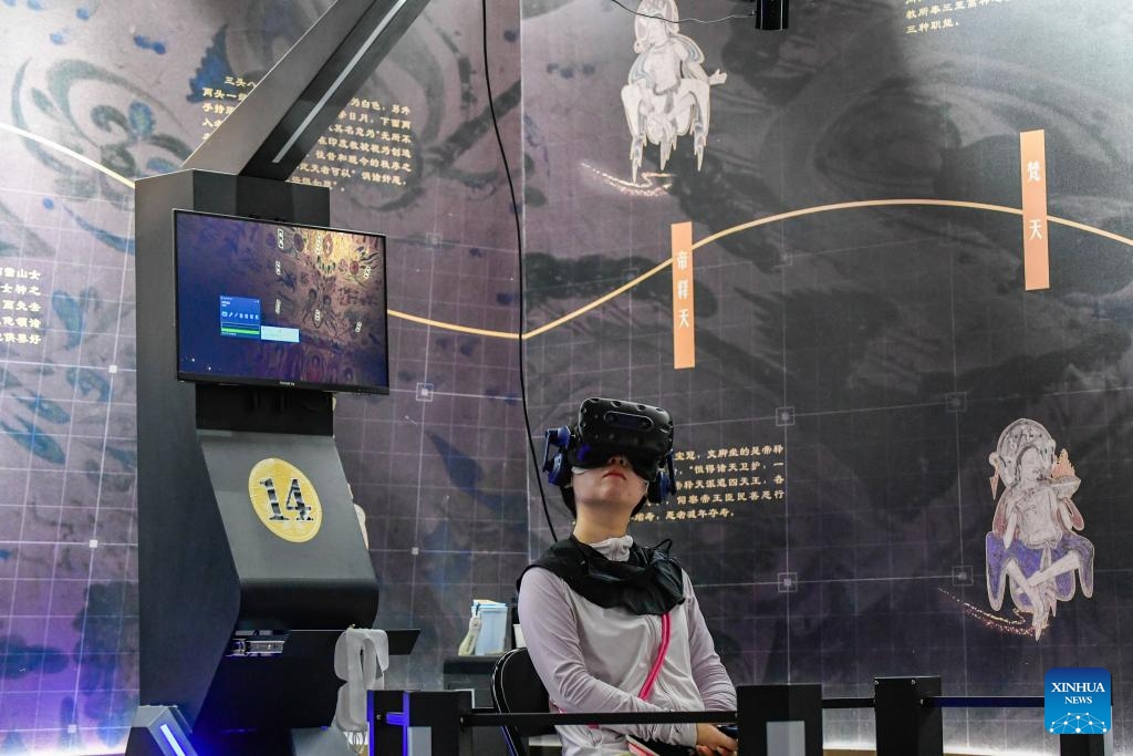 A visitor uses virtual reality (VR) equipment to visit the Mogao Grottoes in Dunhuang, northwest China's Gansu Province, July 22, 2024. A digital exhibition utilizing technologies as 3D modeling and VR devices is held to help visitors have an immersive impression of the culture of Dunhuang. One of the key passes along the ancient Silk Road, Dunhuang is home to the Mogao Grottoes, a UNESCO World Heritage Site that boasts a vast collection of Buddhist artworks. (Photo: Xinhua)