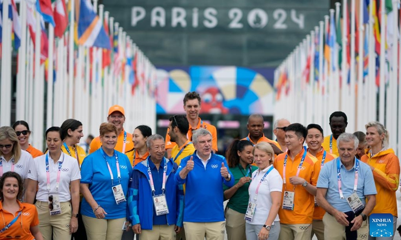 IOC President Thomas Bach (C) gives a thumbs-up while taking a photo with IOC staff members during a tour of the Olympic Village ahead of the Paris 2024 Olympic Games, on July 22, 2024, in Paris, France. (Photo by David Goldman/POOL/Xinhua)