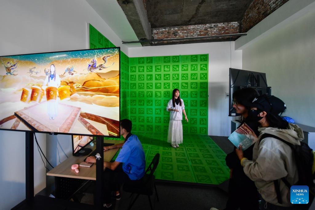 A visitor makes an interactive video at a digital exhibition of Mogao Grottoes in Dunhuang, northwest China's Gansu Province, July 22, 2024. A digital exhibition utilizing technologies as 3D modeling and VR devices is held to help visitors have an immersive impression of the culture of Dunhuang. One of the key passes along the ancient Silk Road, Dunhuang is home to the Mogao Grottoes, a UNESCO World Heritage Site that boasts a vast collection of Buddhist artworks. (Photo: Xinhua)