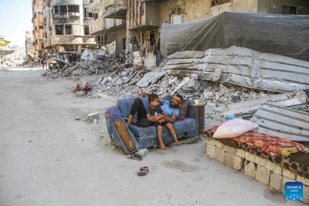 People sit in front of destroyed buildings in the Jabalia refugee camp, northern Gaza Strip, on July 21, 2024. (Photo: Xinhua)