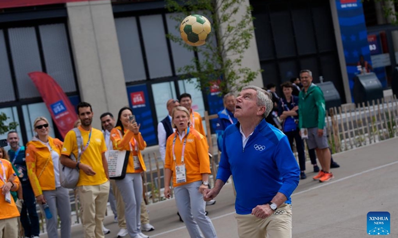 IOC President Thomas Bach (front) controls a ball while touring the Olympic Village ahead of the Paris 2024 Olympic Games, on July 22, 2024, in Paris, France. (Photo by David Goldman/POOL/Xinhua)