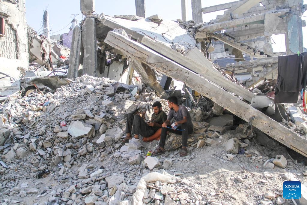 Men sit among rubble in the Jabalia refugee camp, northern Gaza Strip, on July 21, 2024. (Photo: Xinhua)