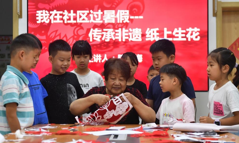 An inheritor of intangible cultural heritage shows children paper-cutting skills at Yinchuan West Road Community of Shinan District, Qingdao, east China's Shandong Province, July 22, 2024. During the summer vacation, the community organized activities of learning intangible cultural heritage to enrich children's holiday experience. (Photo: Xinhua)