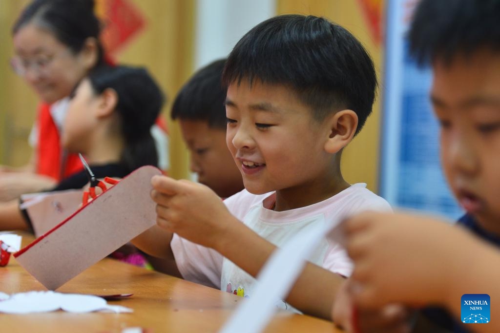 Children try paper-cutting at Yinchuan West Road Community of Shinan District, Qingdao, east China's Shandong Province, July 22, 2024. During the summer vacation, the community organized activities of learning intangible cultural heritage to enrich children's holiday experience (Photo: Xinhua)