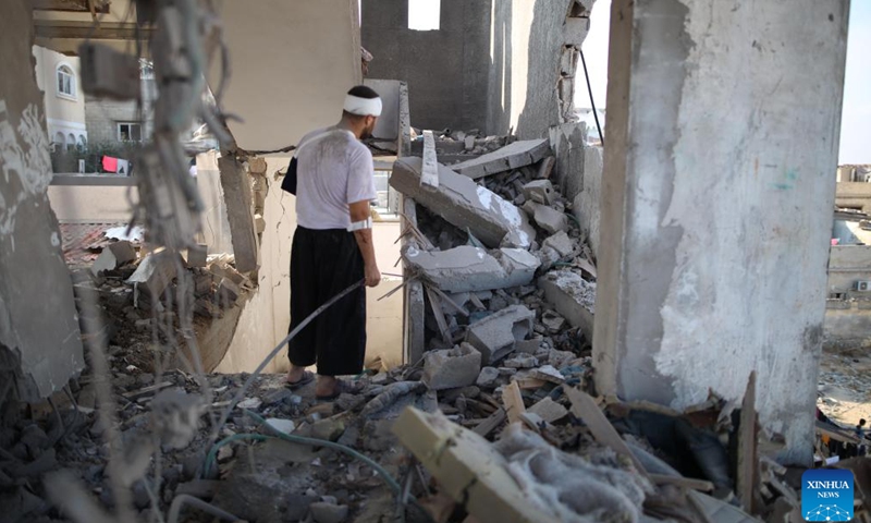 An injured Palestinian man checks a building destroyed in an Israeli airstrike, in Deir al-Balah refugee camp in central Gaza Strip, on July 23, 2024. (Photo: Xinhua)