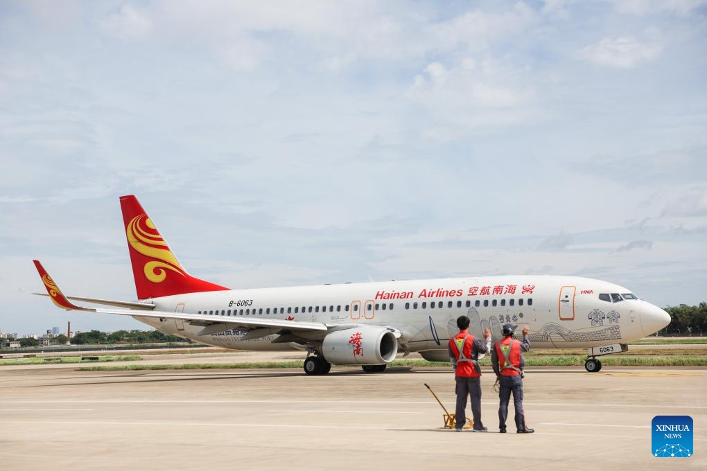 Staff members wave good-bye to an outbound airplane at Meilan International Airport in Haikou, south China's Hainan Province, July 23, 2024. The Meilan International Airport has seen a constant increase in its passenger flow since the beginning of this summer. Staff members of HNA (Hainan Airline) Technic manage to ensure flight safety with thorough maintenance checkups during the peak season. (Photo: Xinhua)