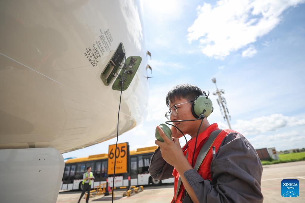 A staff member communicates with the pilot after an airplane landed at Meilan International Airport in Haikou, south China's Hainan Province, July 23, 2024. The Meilan International Airport has seen a constant increase in its passenger flow since the beginning of this summer. Staff members of HNA (Hainan Airline) Technic manage to ensure flight safety with thorough maintenance checkups during the peak season. (Photo: Xinhua)