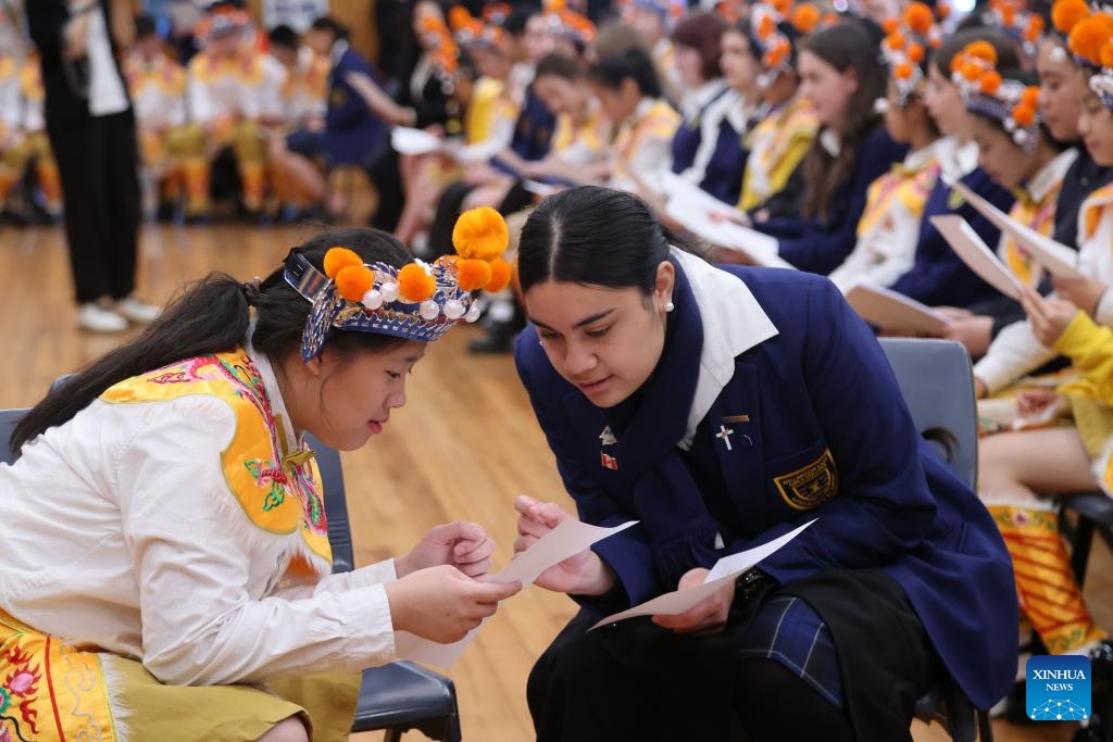 A student of Wellington East Girls' College teaches a member of China's Guangzhou Opera House Children's Choir a Maori song in Wellington, New Zealand, July 24, 2024. Members of Guangzhou Opera House Children's Choir visited Wellington East Girls' College in New Zealand on Wednesday, and held a joint concert with the high school's choir at the opening ceremony of the new semester of the school. (Photo: Xinhua)