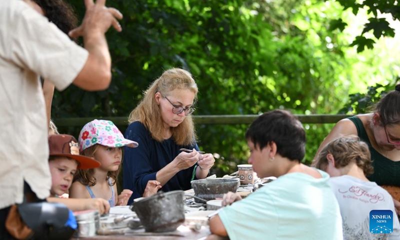 People try soapstone making during the folk festival Mittelalter-Spektakel at Munchenwiler Castle in the Lake Murten region in Switzerland, July 27, 2024. The folk festival was held from Friday to Sunday at Munchenwiler Castle. Various activities, fairs, and folk performances featuring the Middle Ages were organized during the festival. Photo: Xinhua