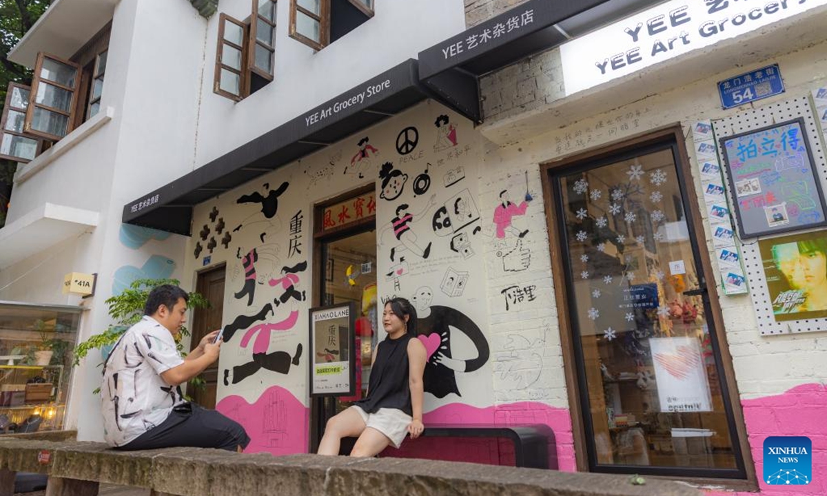 Tourists take photos outside an art grocery store on Longmenhao old street in Nan'an District in southwest China's Chongqing Municipality, July 28, 2024. Longmenhao old street, featuring more than 200 ancient architectures built in different forms and periods, was listed in the first batch of urban renewal pilot projects launched by Chongqing. (Photo: Xinhua)