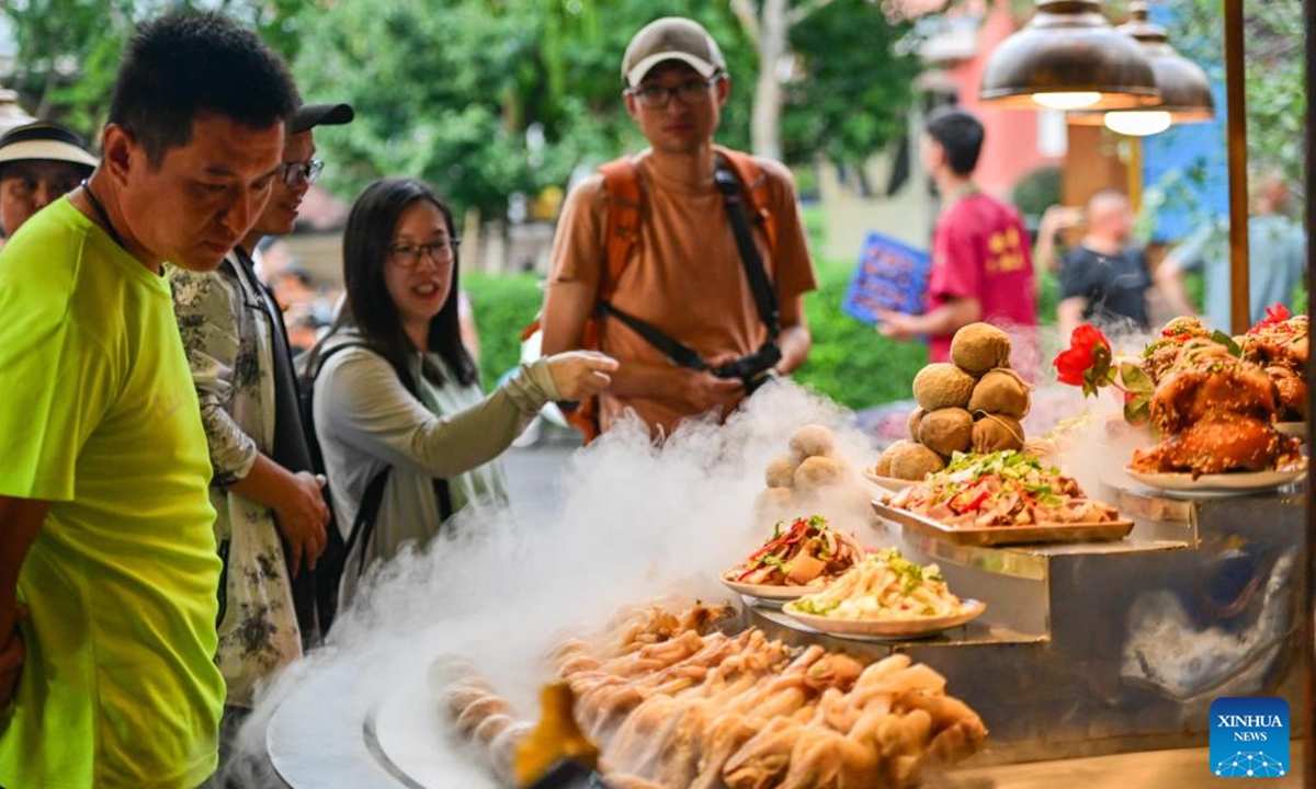 Tourists buy local snacks in Yining City, Ili Kazak Autonomous Prefecture, northwest China's Xinjiang Uygur Autonomous Region, July 28, 2024.

Xinjiang is experiencing a tourism boom this year. Covering approximately one-sixth of China's land area, Xinjiang boasts diverse and unique natural landscapes, as well as rich historical and cultural tourism resources.(Photo: Xinhua)