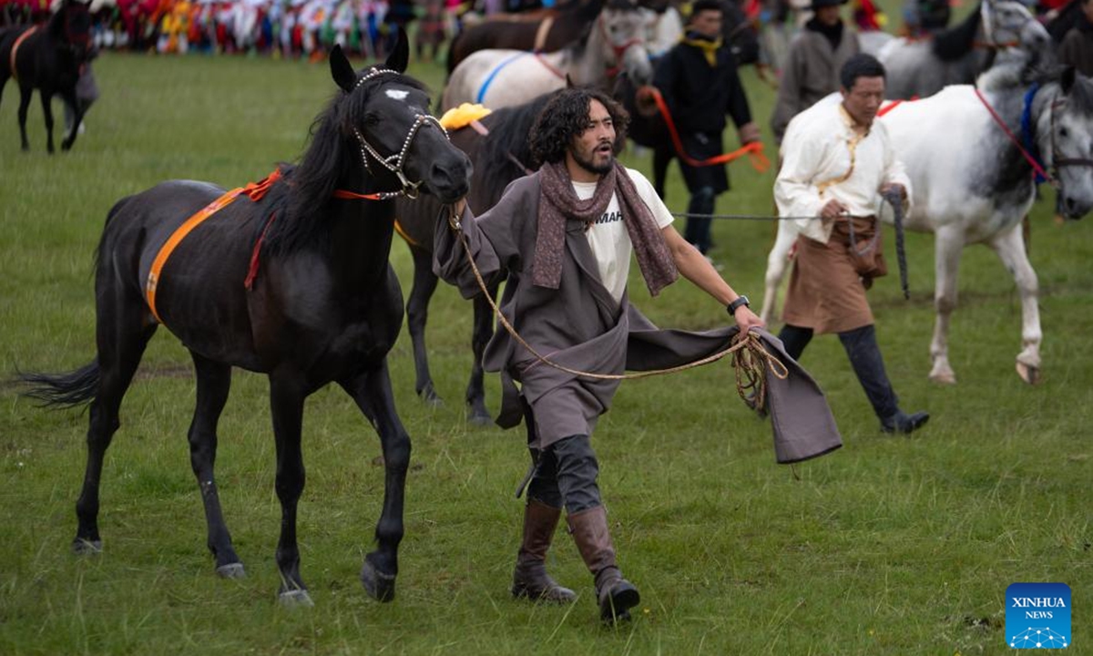 A villager leading a horse walks into a court for horse racing on a grassland in Baiyu County, Garze Tibetan Autonomous Prefecture, southwest China's Sichuan Province, July 27, 2024. A rural folk event consisting of performances, horse racing, yak beauty contest, and other activities have attracted many participants. (Photo: Xinhua)