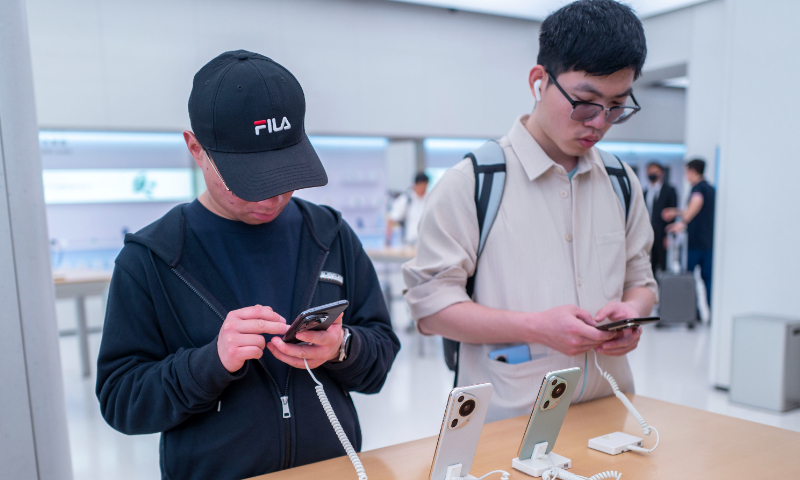 Consumers experience smartphones at a mobile store in Shanghai on April 22, 2024. Photo: VCG