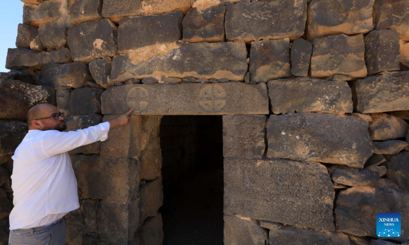 A guide introduces a structure at the archaeological site of Umm al-Jimal in northern Jordan, Aug. 13, 2024. Umm al-Jimal, located in northern Jordan, is one of the country's significant cultural heritage sites which was inscribed on the World Heritage List by the United Nations Educational, Scientific and Cultural Organization (UNESCO) in 2024. (Photo: Xinhua)