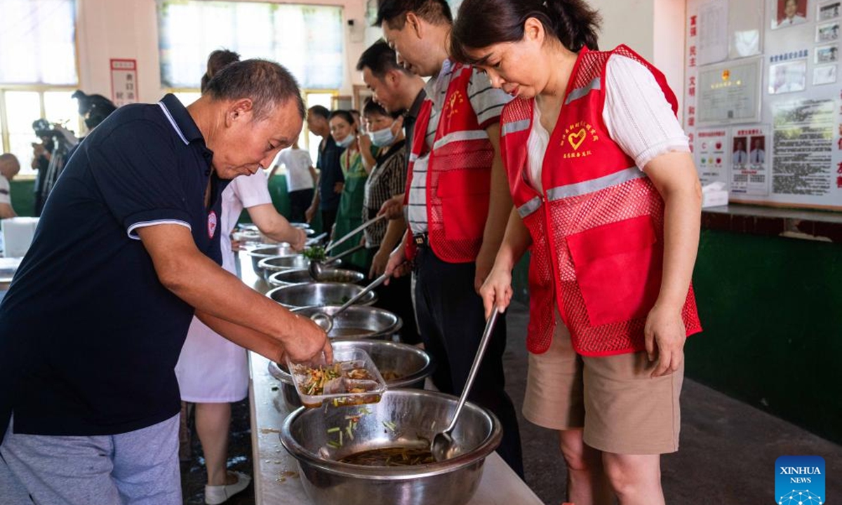 Volunteers serve meal for relocated residents at a relocation site in a school in Xiangtan County, central China's Hunan Province, July 30, 2024. Heavy rainstorms in the aftermath of Typhoon Gaemi have wreaked havoc across Hunan. In Xiangtan County, three dike breaches occurred in the Juanshui River in the past few days, prompting the evacuation of thousands of residents. (Photo: Xinhua)