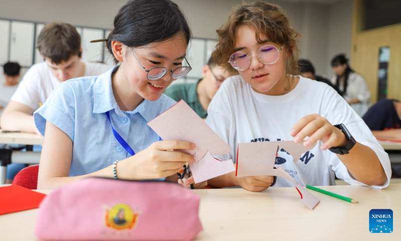 Chinese and Russian students make paper-cut works at Qingdao Hengxing University in Qingdao, east China's Shandong Province, Aug. 12, 2024. A summer camp themed on Chinese learning was recently held in Qingdao, with activities for 12 Russian students featuring traditional intangible cultural heritages. (Photo: Xinhua)