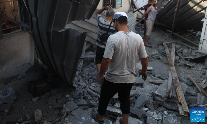 People walk through the rubble after an Israeli airstrike in the Nuseirat refugee camp, central Gaza Strip, on Aug. 12, 2024. The Palestinian death toll from ongoing Israeli attacks on the Gaza Strip has risen to 39,897, Gaza-based health authorities said in a statement on Monday. (Photo by Marwan Dawood/Xinhua)