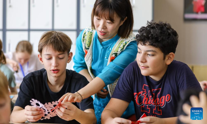 A teacher helps Russian students make paper-cut works at Qingdao Hengxing University in Qingdao, east China's Shandong Province, Aug. 12, 2024. A summer camp themed on Chinese learning was recently held in Qingdao, with activities for 12 Russian students featuring traditional intangible cultural heritages. (Photo: Xinhua)