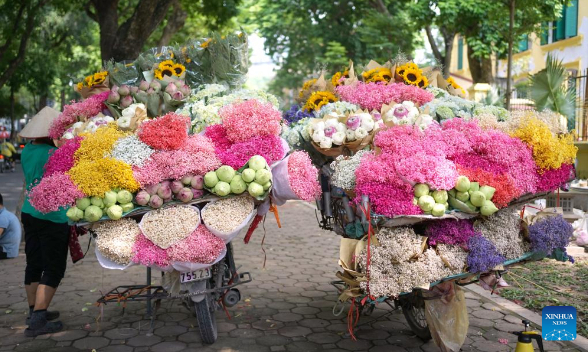 Two mobile stalls laden with various flowers park on the street of Hanoi, Vietnam, Aug. 16, 2024. (Photo: Xinhua)