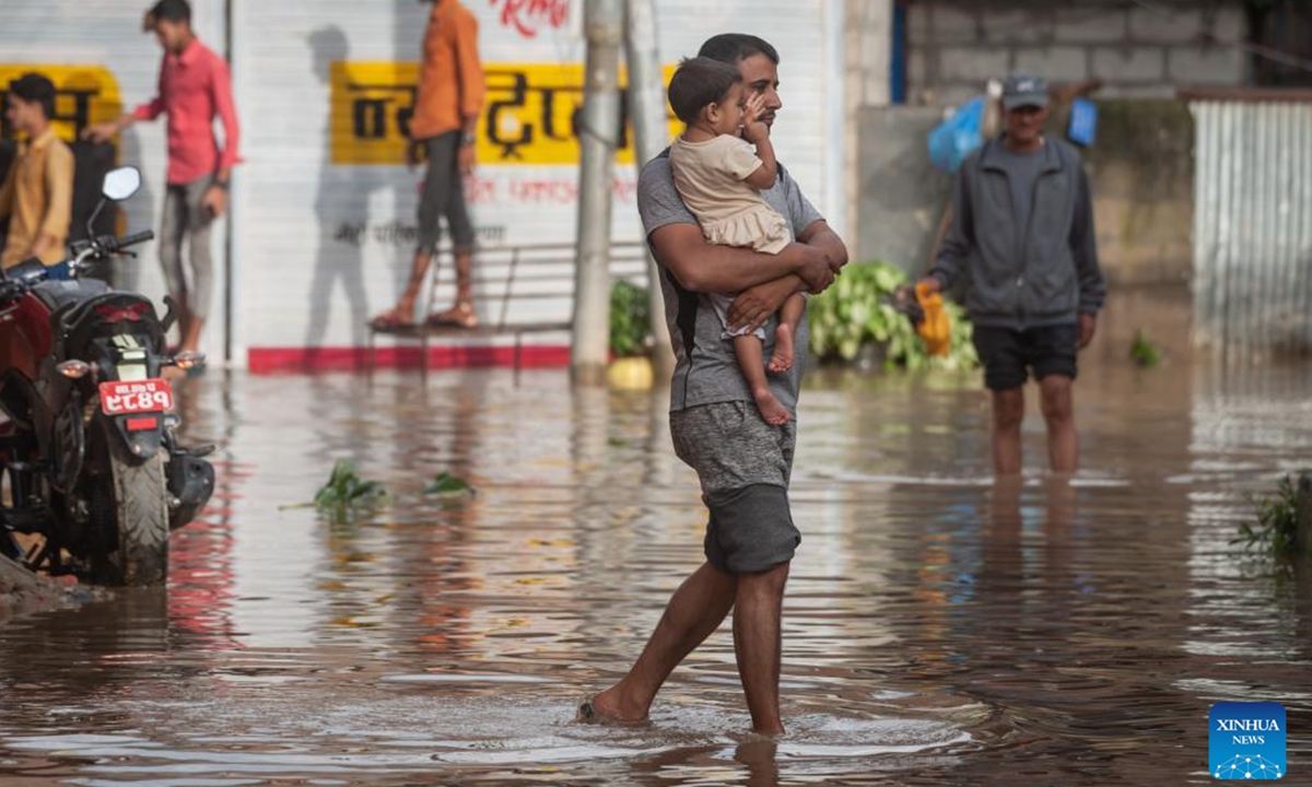 People wade through a waterlogged road after heavy rains in Lalitpur, Nepal, July 31, 2024. (Photo: Xinhua)