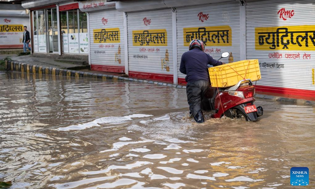 A motorcyclist wades through a waterlogged road after heavy rains in Lalitpur, Nepal, July 31, 2024. (Photo: Xinhua)