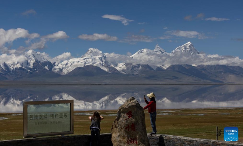 People take photos of Mount Chomolhari from a wetland park in Yadong County of Xigaze City, southwest China's Xizang Autonomous Region, Aug. 1, 2024. (Xinhua/Jiang Fan)