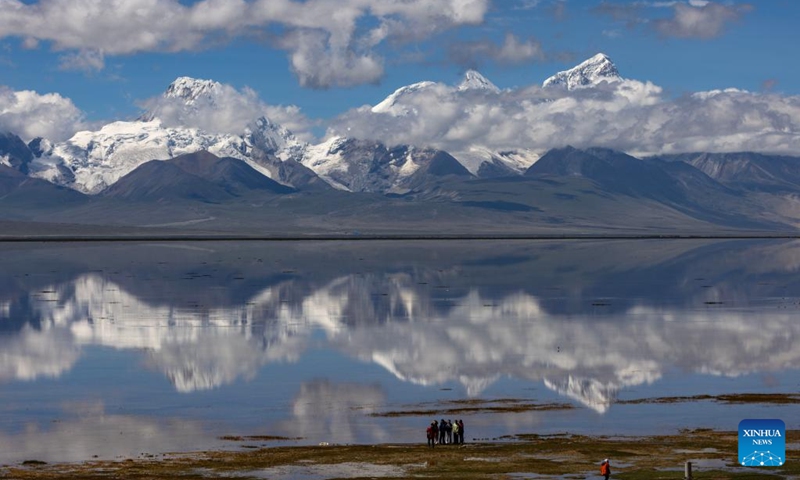 People take photos of Mount Chomolhari from a wetland park in Yadong County of Xigaze City, southwest China's Xizang Autonomous Region, Aug. 1, 2024. (Xinhua/Jiang Fan)