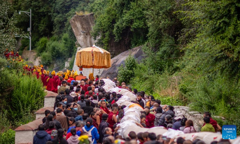 People carry an enormous rolled-up thangka painting of Buddha towards a platform on the hillside for sunning in Lhasa, southwest China's Xizang Autonomous Region, Aug. 4, 2024. Celebrations marking the traditional Shoton Festival, or Yogurt Festival, began in Lhasa, capital of southwest China's Xizang Autonomous Region, on Sunday. Photo: Xinhua