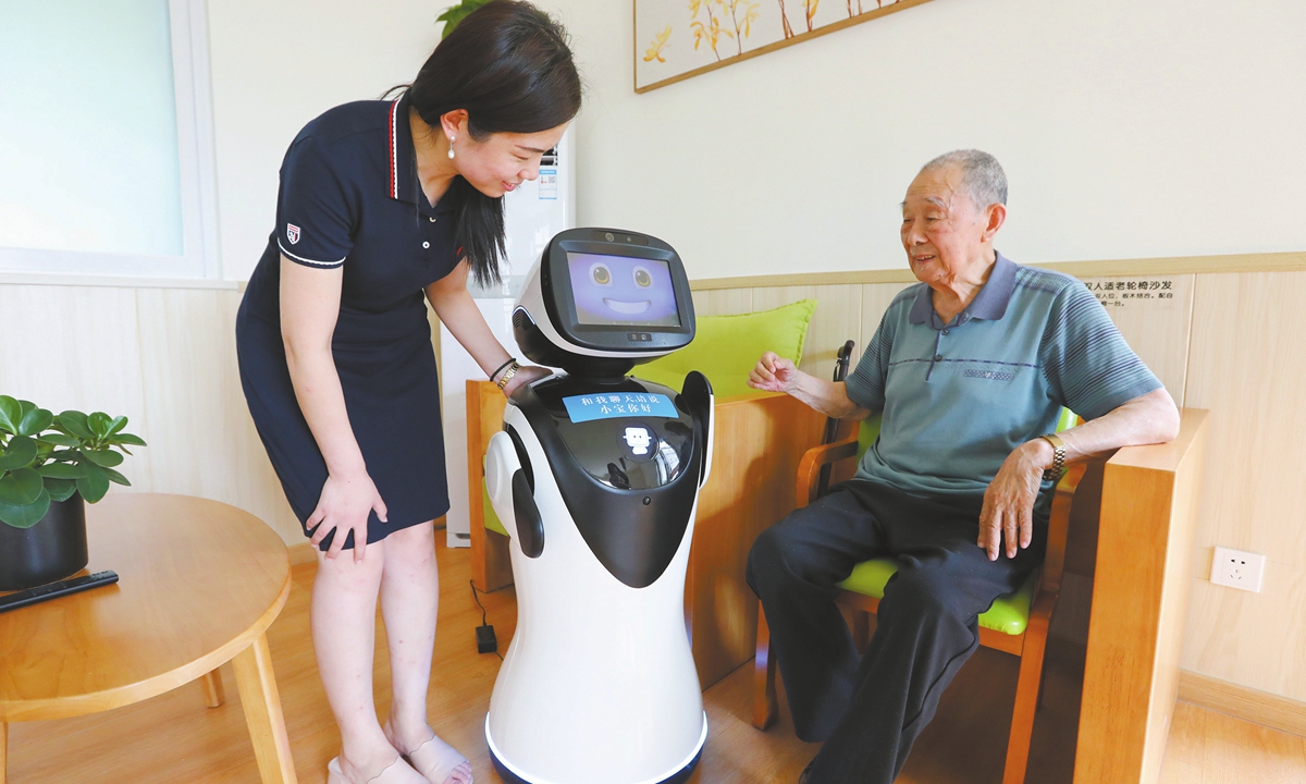 A retired man interacts with an AI robot under the guidance of an assistant in Zhengzhou,<strong></strong> Central China's Henan Province. Photo: VCG