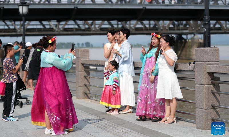 Tourists pose for photos along the Yalu River in Dandong City, northeast China's Liaoning Province, Aug. 2, 2024. Tourism service has resumed as the water level in the Yalu River recedes and the riverside roads are reopened to traffic. Photo: Xinhua