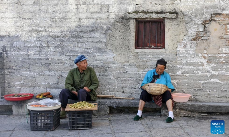 Villagers chat in Benzhai Village, Xixiu District, Anshun City, southwest China's Guizhou Province, July 23, 2024. In Anshun City, southwest China's Guizhou Province, ancient stone buildings and unique local traditions have made a cluster of villages popular tourist destinations for many visitors. The stone-structured Tunpu residential buildings were built in the Ming Dynasty (1368-1644), when some troops were sent to Anshun, where they built villages and turned the neighborhood into farmland for growing crops. Their descendants have lived there over generations, and formed the unique Tunpu culture which preserved distinctive customs, architectures, operas and costumes of ancient times. Photo: Xinhua