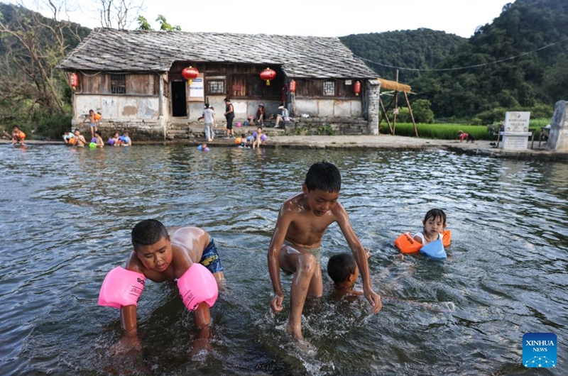 Kids play in the water in Baojiatun Village, Xixiu District, Anshun City, southwest China's Guizhou Province, July 24, 2024. In Anshun City, southwest China's Guizhou Province, ancient stone buildings and unique local traditions have made a cluster of villages popular tourist destinations for many visitors. The stone-structured Tunpu residential buildings were built in the Ming Dynasty (1368-1644), when some troops were sent to Anshun, where they built villages and turned the neighborhood into farmland for growing crops. Their descendants have lived there over generations, and formed the unique Tunpu culture which preserved distinctive customs, architectures, operas and costumes of ancient times. Photo: Xinhua