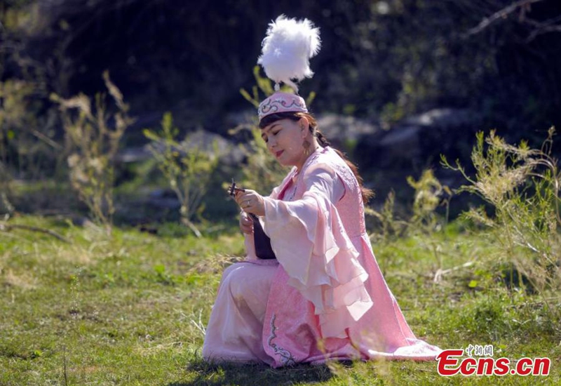 An artist adjusts her tamboura at a park in Urumqi, northwest China's Xinjiang Uyghur Autonomous Region, Aug. 3, 2024. Photo: China News Service