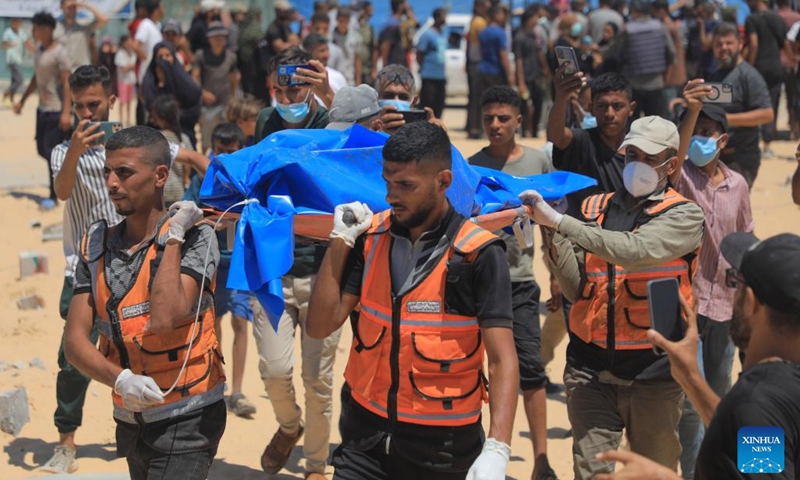 Workers carry bodies of unidentified Palestinians killed by the Israeli army in the southern Gaza Strip city of Khan Younis, on Aug. 5, 2024. Israel had returned the bodies of 89 Palestinians killed by the Israeli army in the Gaza Strip, the Hamas-run Gaza government media office said on Monday. (Photo: Xinhua)