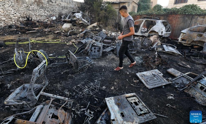 A man walks past vehicles burned during clashes between Palestinian protesters and Israeli settlers in the West Bank city of Nablus, on Aug. 5, 2024.(Photo: Xinhua)