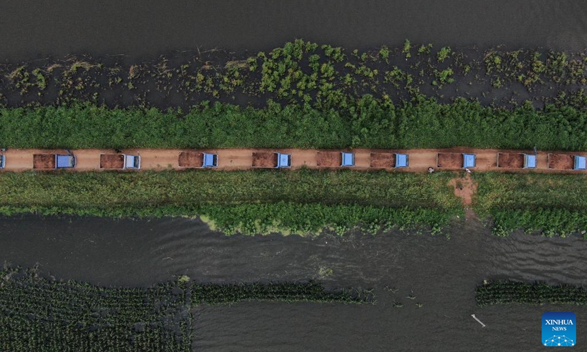 This aerial drone photo taken on Aug. 7, 2024 shows emergency workers transporting building materials to reinforce a newly repaired dike in Tieling, northeast China's Liaoning Province. The dike breach at a river in northeast China's Liaoning Province was sealed at 4:27 a.m. Wednesday after emergency workers had worked around the clock to repair it, according to local authorities.  (Photo: Xinhua)