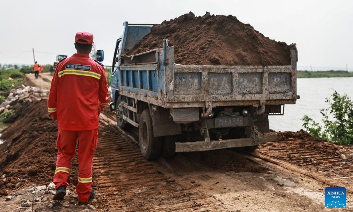 Rescuers transport building materials to reinforce a newly repaired dike in Tieling, northeast China's Liaoning Province, Aug. 7, 2024. The dike breach at a river in northeast China's Liaoning Province was sealed at 4:27 a.m. Wednesday after emergency workers had worked around the clock to repair it, according to local authorities.  (Photo: Xinhua)