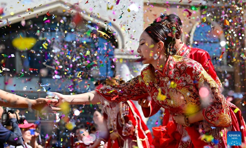 A newly-wed couple distribute candies during a group wedding at the Xinjiang International Grand Bazaar in Urumqi, northwest China's Xinjiang Uygur Autonomous Region, Aug. 10, 2024. The group wedding was held here on Saturday on the occasion of the Qixi Festival, also known Chinese Valentine's Day. Photo: Xinhua