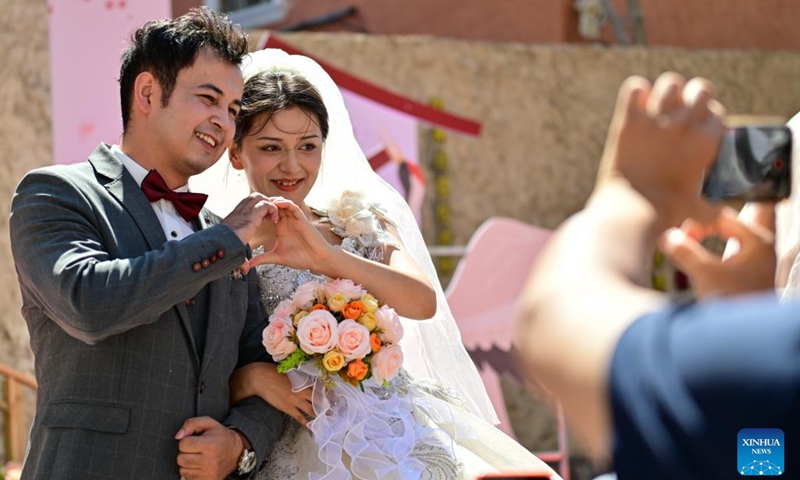 A newly-wed couple pose for photos during a group wedding at the Xinjiang International Grand Bazaar in Urumqi, northwest China's Xinjiang Uygur Autonomous Region, Aug. 10, 2024. The group wedding was held here on Saturday on the occasion of the Qixi Festival, also known Chinese Valentine's Day. Photo: Xinhua