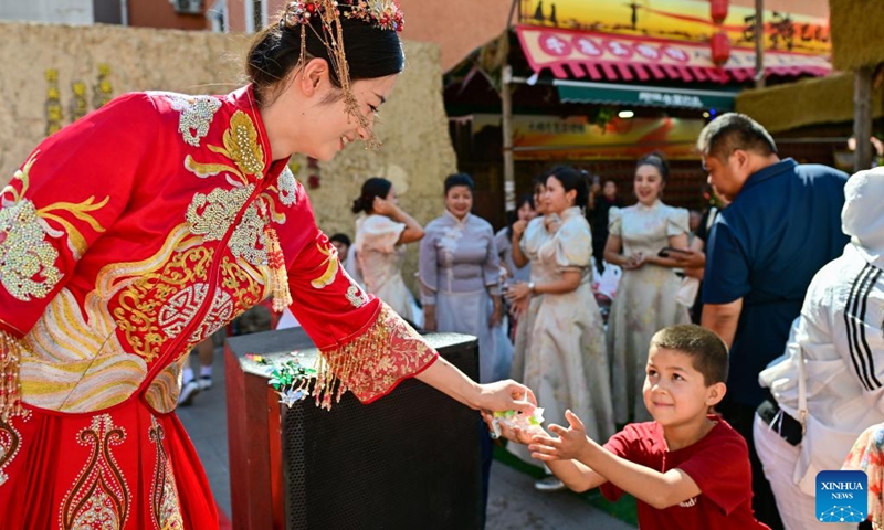 A bride distributes candies during a group wedding at the Xinjiang International Grand Bazaar in Urumqi, northwest China's Xinjiang Uygur Autonomous Region, Aug. 10, 2024. The group wedding was held here on Saturday on the occasion of the Qixi Festival, also known Chinese Valentine's Day. Photo: Xinhua