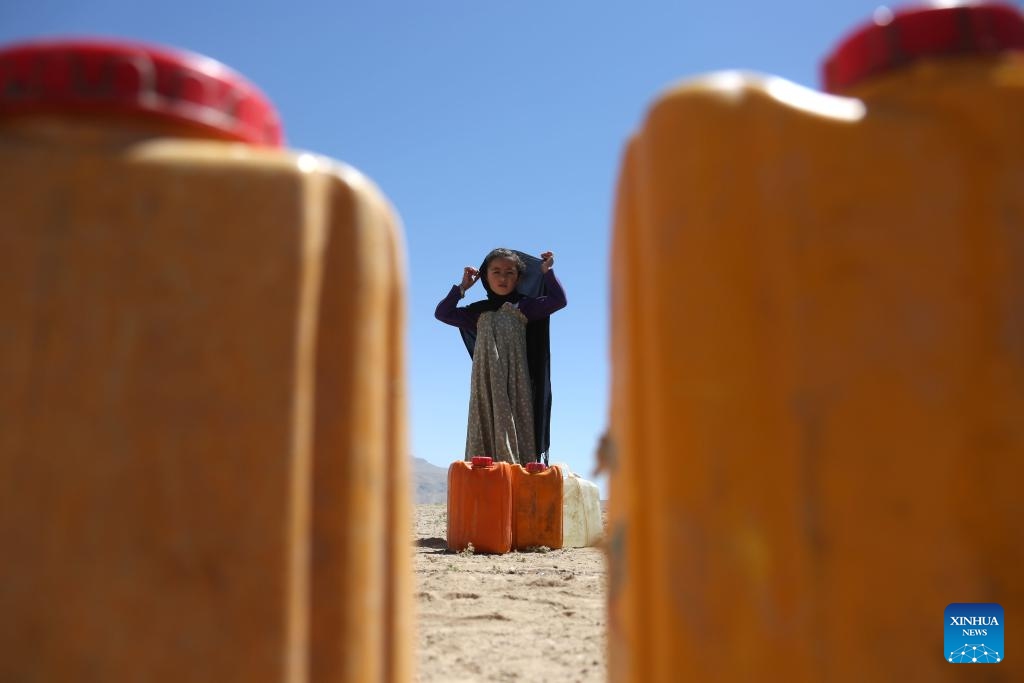 A girl stands in front of water barrels at a relocation site for flood survivors in Firoz Koh, Ghor province, Afghanistan, July 27, 2024. (Photo: Xinhua)