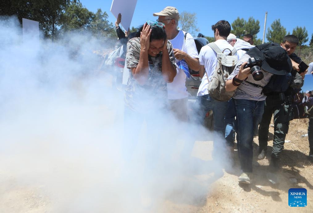 Palestinians and foreign activists take cover from tear gas during a demonstration against the Israeli confiscation of land in Beit Jala, near the West Bank city of Bethlehem, on Aug. 8, 2024. (Photo: Xinhua)