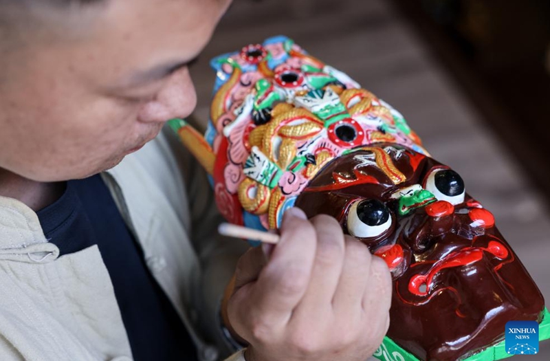 Bao Bo, an inheritor of Anshun woodcarving, colors a Dixi mask in Jiuzhou ancient town scenic area of Anshun City, southwest China's Guizhou Province, July 25, 2024. Photo: Xinhua