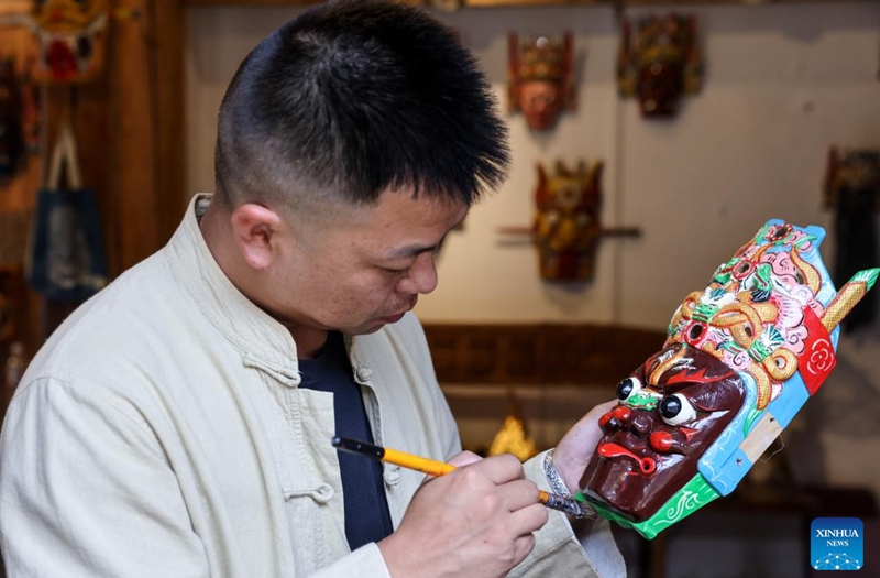 Bao Bo, an inheritor of Anshun woodcarving, colors a Dixi mask in Jiuzhou ancient town scenic area of Anshun City, southwest China's Guizhou Province, July 25, 2024. Photo: Xinhua