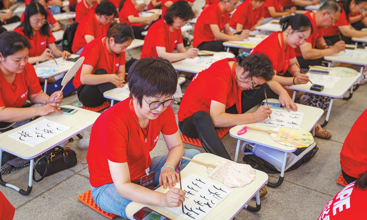 At least 350 family education experts from across China write Nüshu on lacquer fans with Chinese brushes at the National Museum of Chinese Writing in Anyang, Central China's Henan Province, on June 21, 2024. Photo: VCG