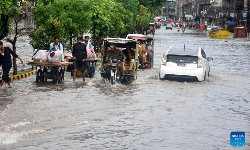 People and vehicles wade through floodwater in a street after heavy monsoon rain in Lahore, Pakistan on Aug. 11, 2024. Photo: Xinhua