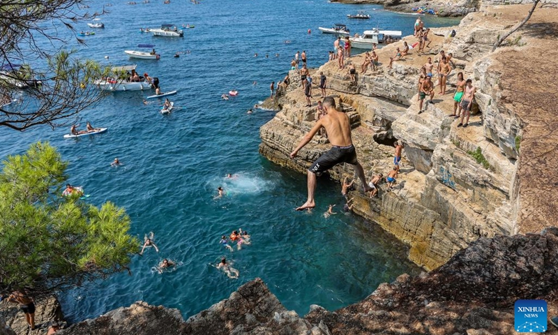 A man dives into the sea to cool off from the cliff at the Seagull's Rocks Beach in Pula, Croatia on Aug. 14, 2024. The maximum temperature in Pula reaches 35 degrees Celsius during the day. (Photo: Xinhua)