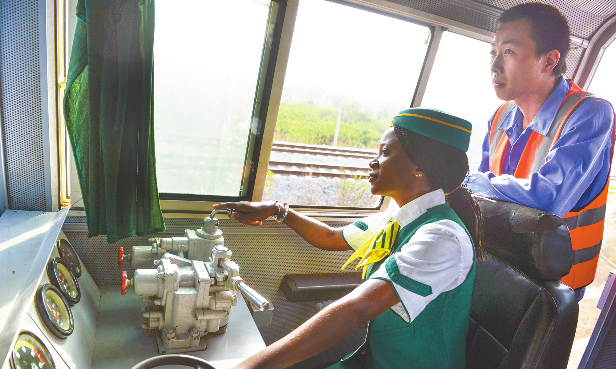 Issah Abiola (left), Nigeria's first female train driver, operates equipment in the driver's room of a train. Photo: Courtesy of CCECC