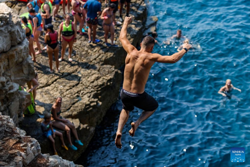 A man dives into the sea to cool off from the cliff at the Seagull's Rocks Beach in Pula, Croatia on Aug. 14, 2024. The maximum temperature in Pula reaches 35 degrees Celsius during the day. (Photo: Xinhua)